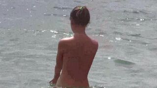 A group of people relaxes naked on the beach and enjoys the day