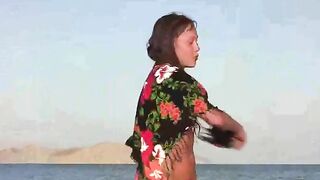 A member shows a girl the benefits of nudity on the beach