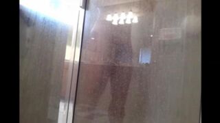 A man washes himself in the shower, but he does not know that he is being watched