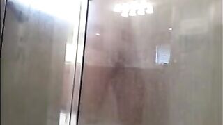 A man washes himself in the shower, but he does not know that he is being watched