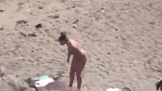 A pair of naturists sunbathing completely naked on the sea coast
