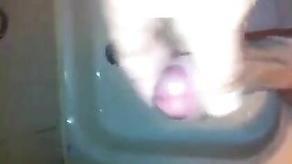 The kid caresses his cock in the shower with his hand