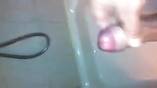 The kid caresses his cock in the shower with his hand
