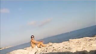 A girl sunbathes completely naked on the beach