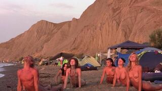 A group of naked people are playing volleyball together