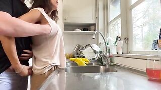 A mature woman with big tits is being fucked from behind in the kitchen
